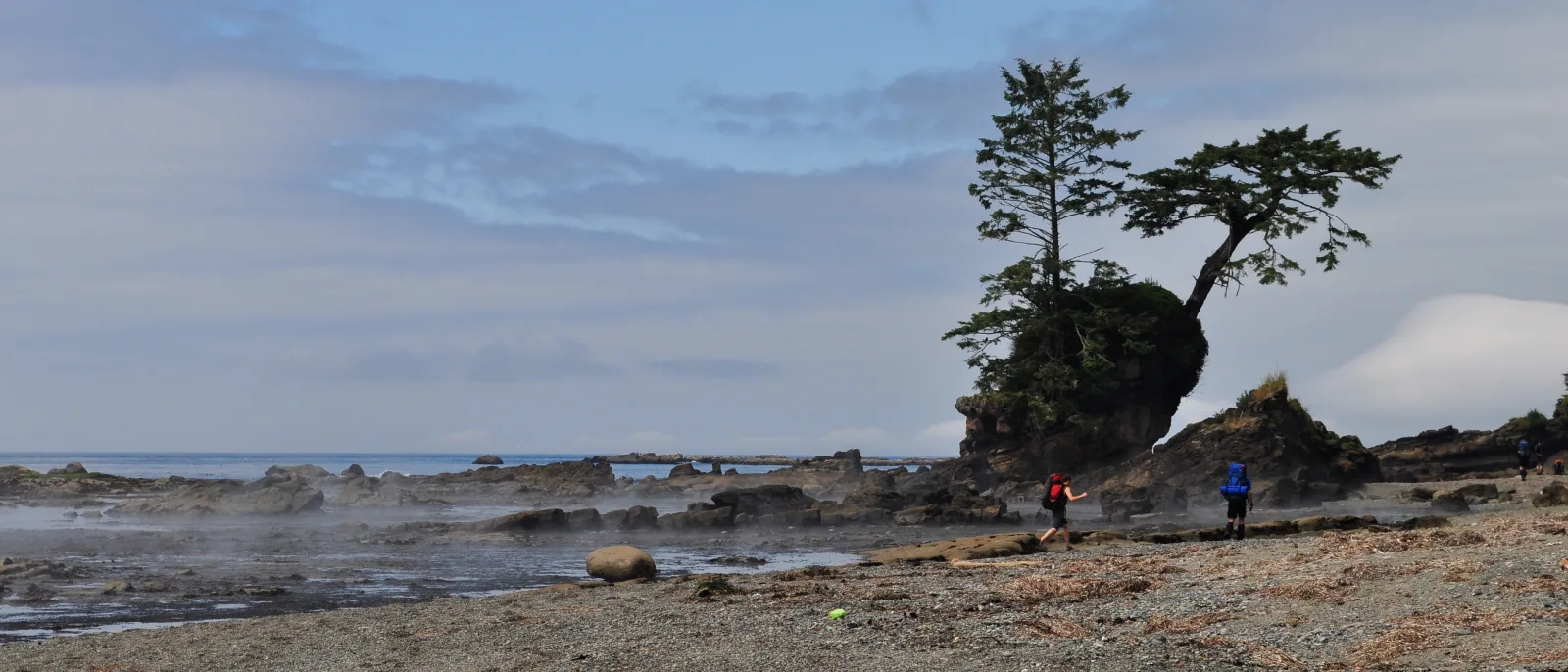 Wędrowcy z plecakami na skalistym brzegu West Coast Trail na wyspie Vancouver